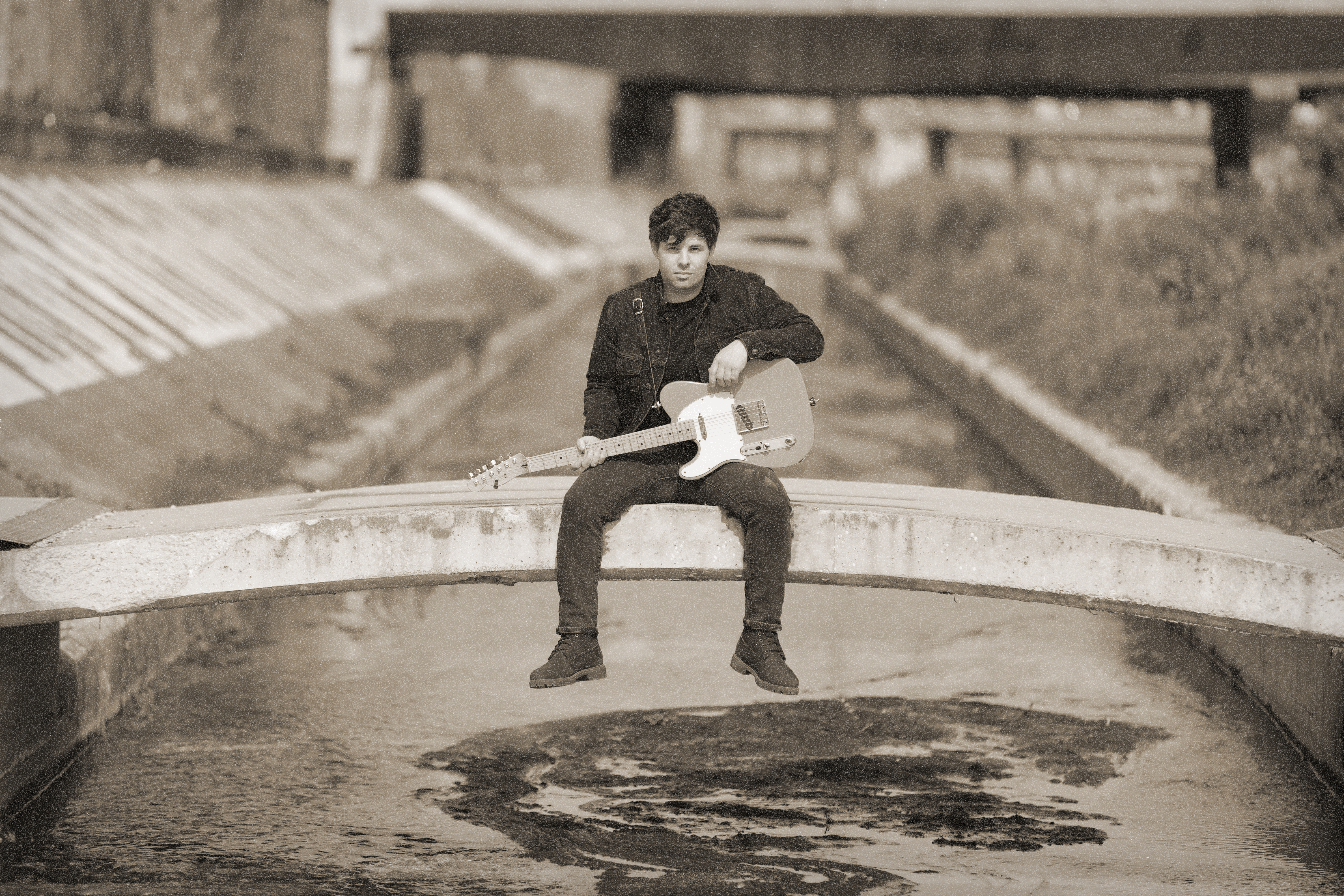 Nick Saxton perched on a bridge over a river